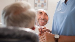man smiling in dental mirror