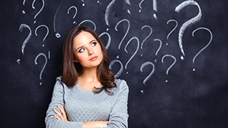 woman in front of chalkboard covered in question marks