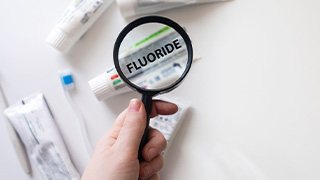 Magnifying glass focused on “Fluoride” on tube of toothpaste