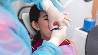 Gloved hands applying fluoride trays to girl’s teeth
