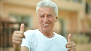 older man smiling doing thumbs up