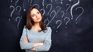 young woman standing in front of chalkboard with question marks