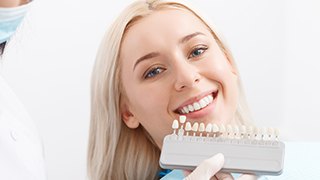 Woman comparing smile to tooth shading chart