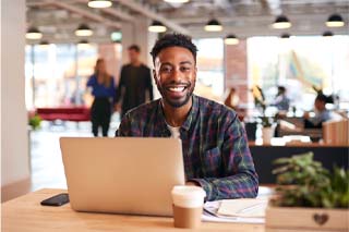 Man smiling with working on laptop in office