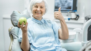 older woman holding green apple