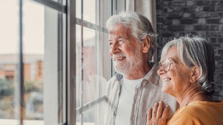 aa couple smiling with dentures and looking out the window 
