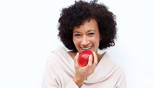 smiling woman biting into a red apple 