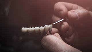 Lab technician painting replacement teeth