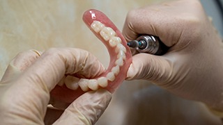 Lab technician filing dentures