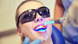 A curing light being used on a female patient