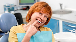 dental patient pointing to her smile 