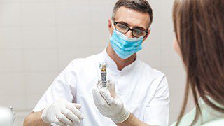 dentist showing a patient a dental implant model 