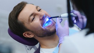 Dentist shining a special light on patient’s teeth