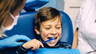 little boy brushing teeth in dental chair