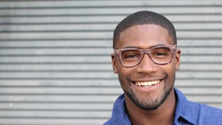 person with wood-colored glasses smiling