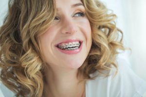 a young woman with blonde hair smiling and showing off her metal braces