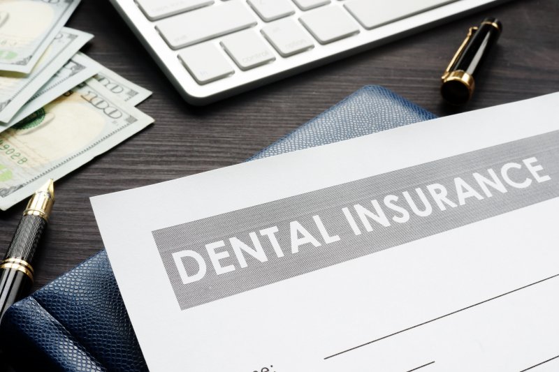 Dental insurance form on desk with money and pens