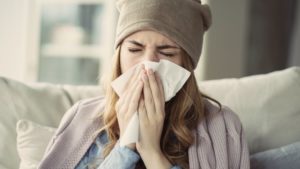 young woman with a cold blowing her nose 