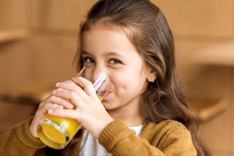 Closeup of young girl drinking orange juice