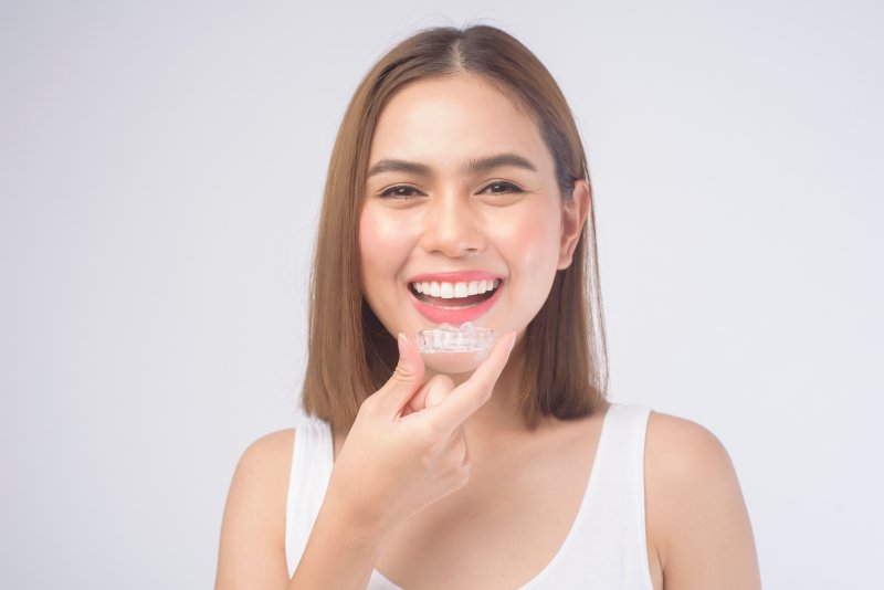 Girl holding a clear aligner in front of her smile