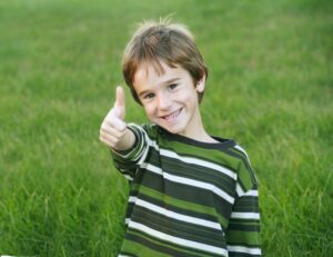 Kid smiling and giving thumbs up. 